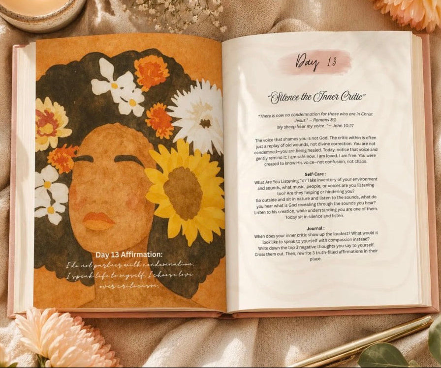 An open journal or book laid on a beige fabric surface with flowers, a candle, and a gold pen around it. The left page shows a stylized illustration of a woman's face with flowers and the text 'Day 13 Affirmation.